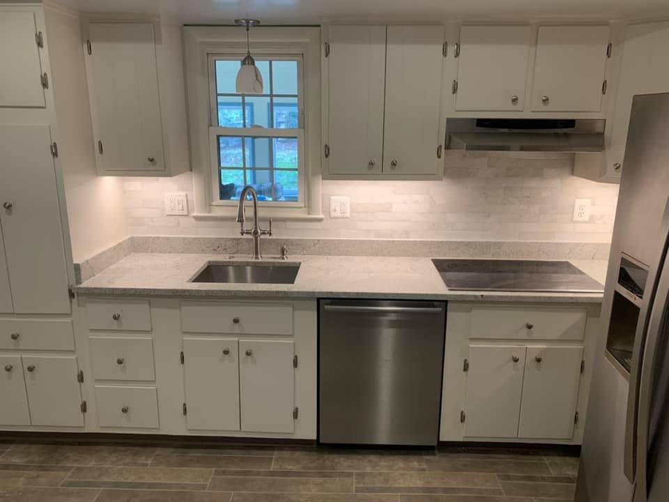 White kitchen cabinets with stainless steel appliances and light countertops.