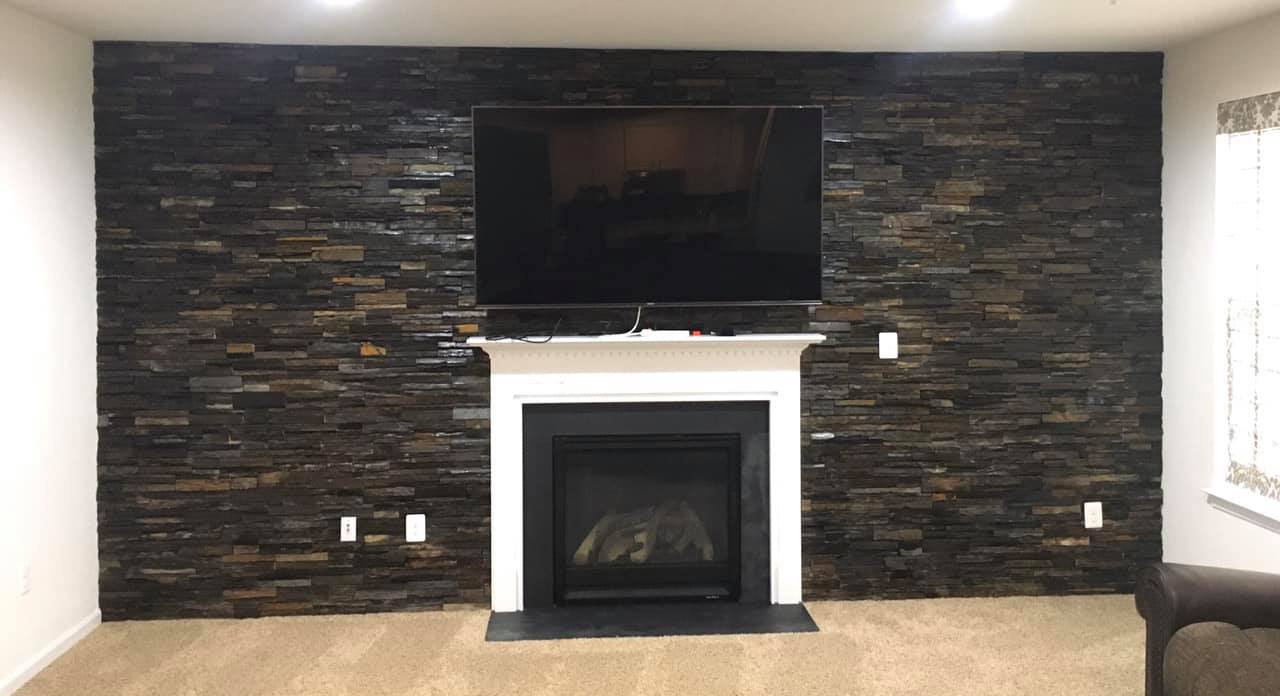 Black stone accent wall with fireplace and mounted TV.