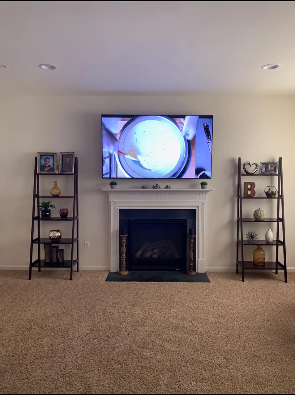 Living room with fireplace, TV above. Two bookshelves flank the fireplace, displaying decorative items.
