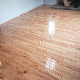 Light-colored hardwood floor in a room. Sunlight reflects off the glossy surface.