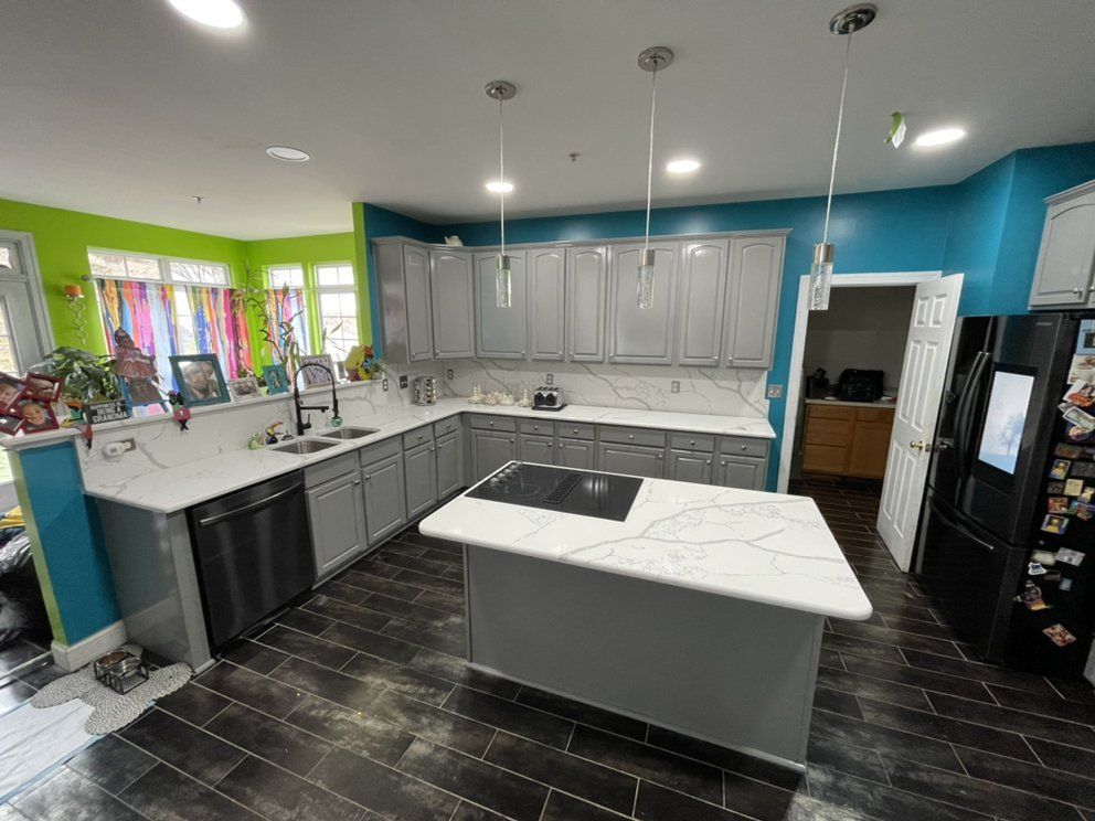 Modern kitchen with gray cabinets, white countertops, and black appliances.