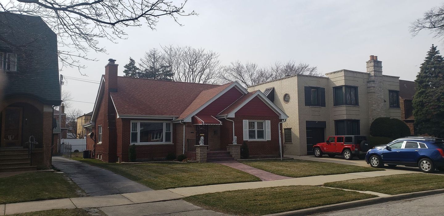 A blue car is parked in front of a house
