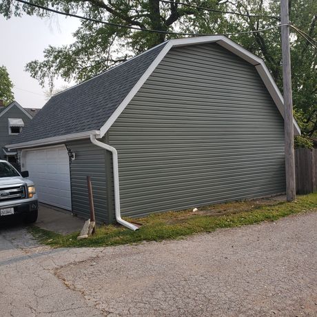 A white truck is parked in front of a large barn.