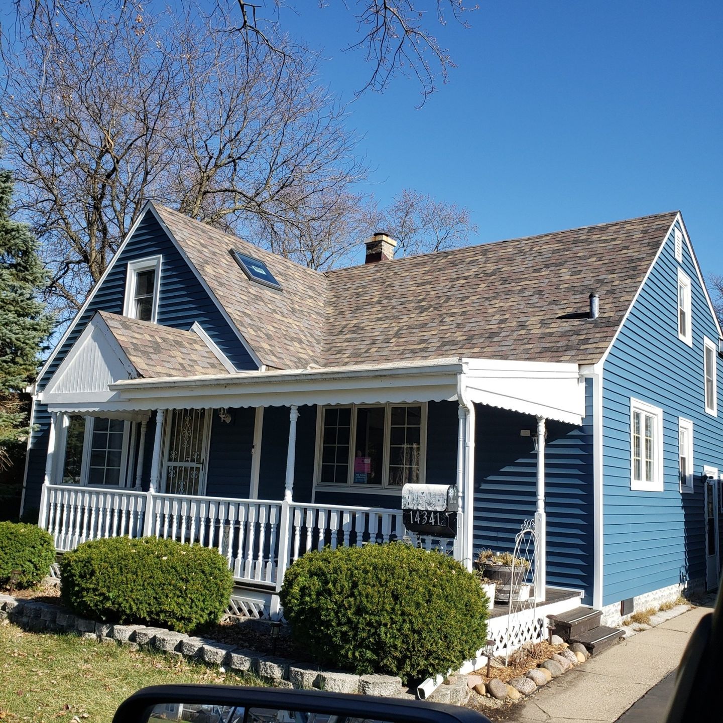 A blue house with a porch and a sign that says home