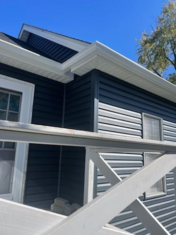 A black house with white siding and a white railing
