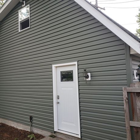 A green house with a white door and window.