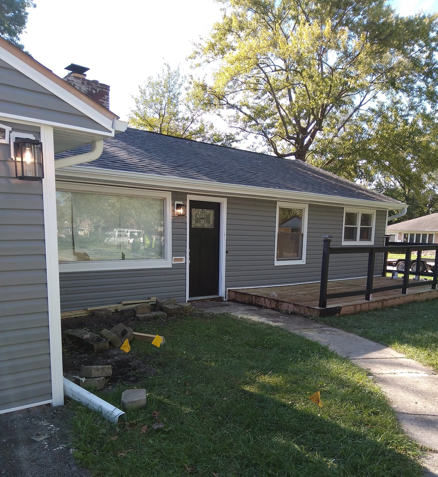 A gray house with a black door and a fence in front of it.