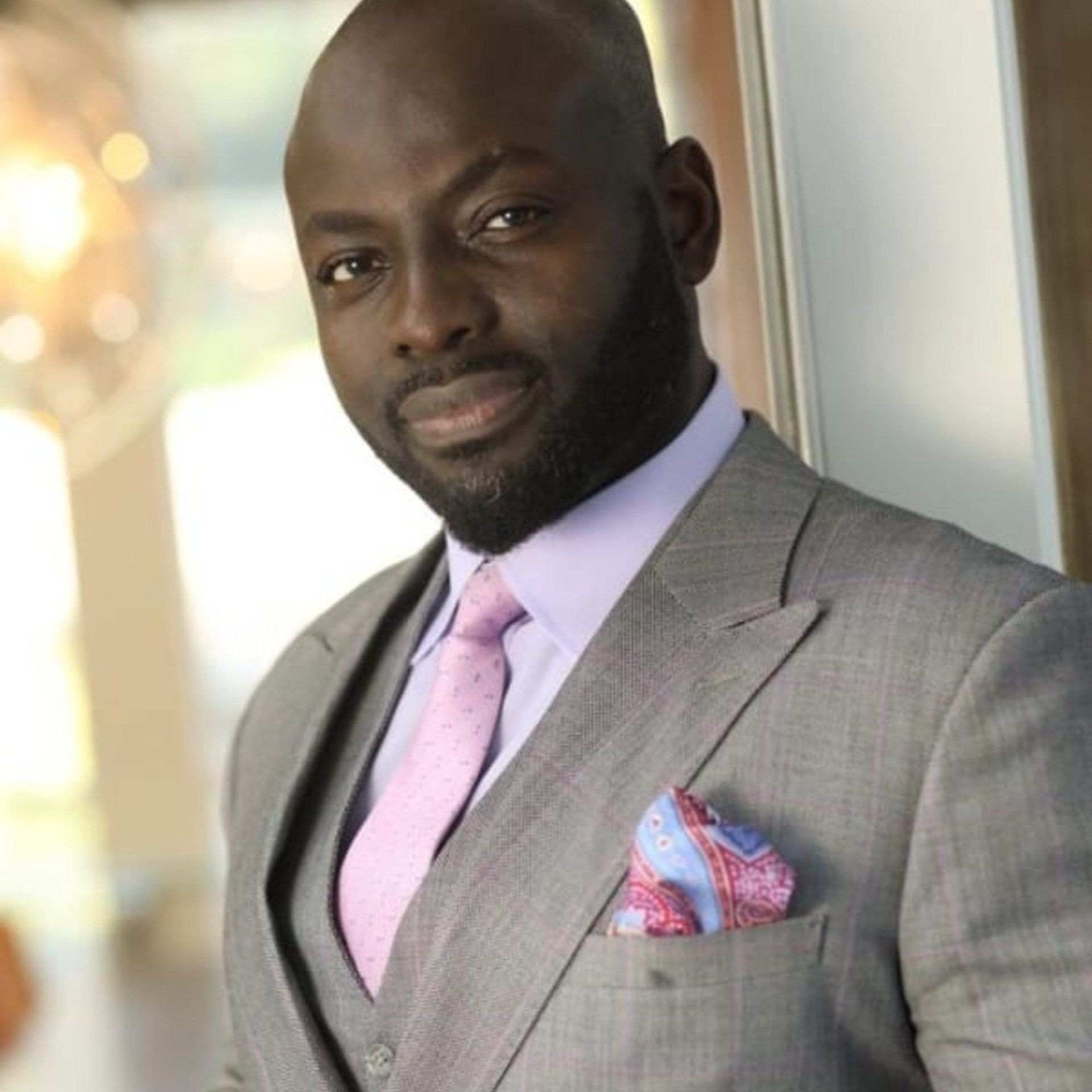 A man in a suit and tie is leaning against a wall