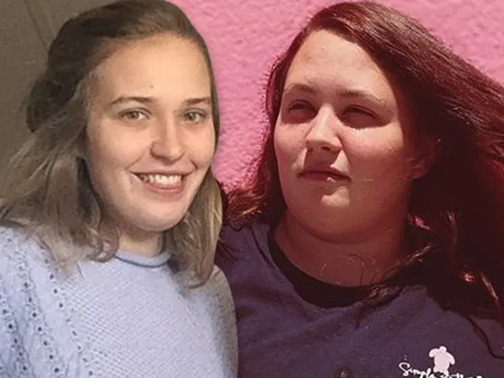 Two women are posing for a picture together in front of a pink wall.