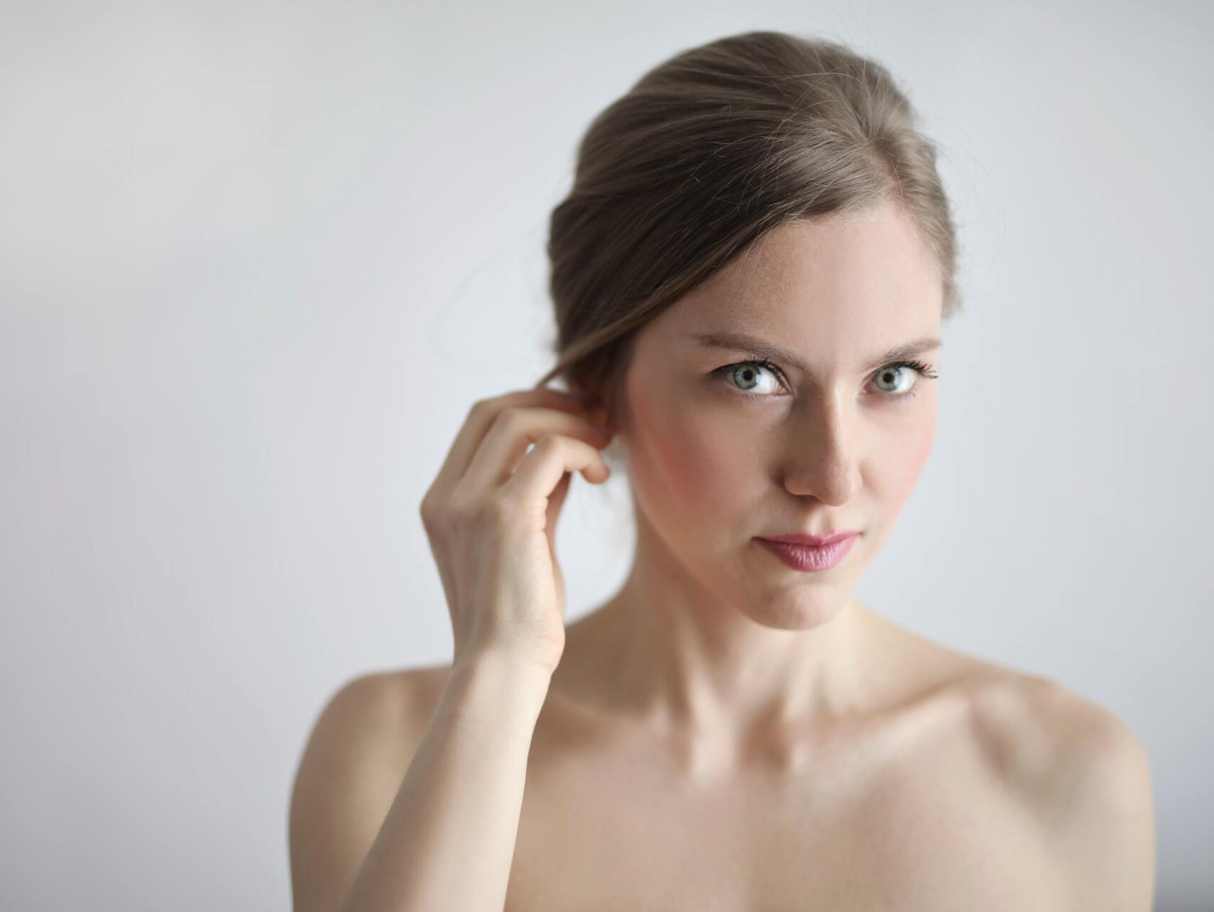 A woman is touching her ear with her hand and looking at the camera.