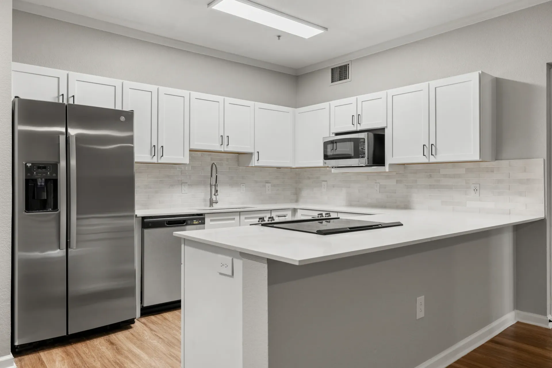 Bright, modern kitchen with white cabinets, stainless steel appliances, and an island at Briargate on Main apartments in Parker, CO.