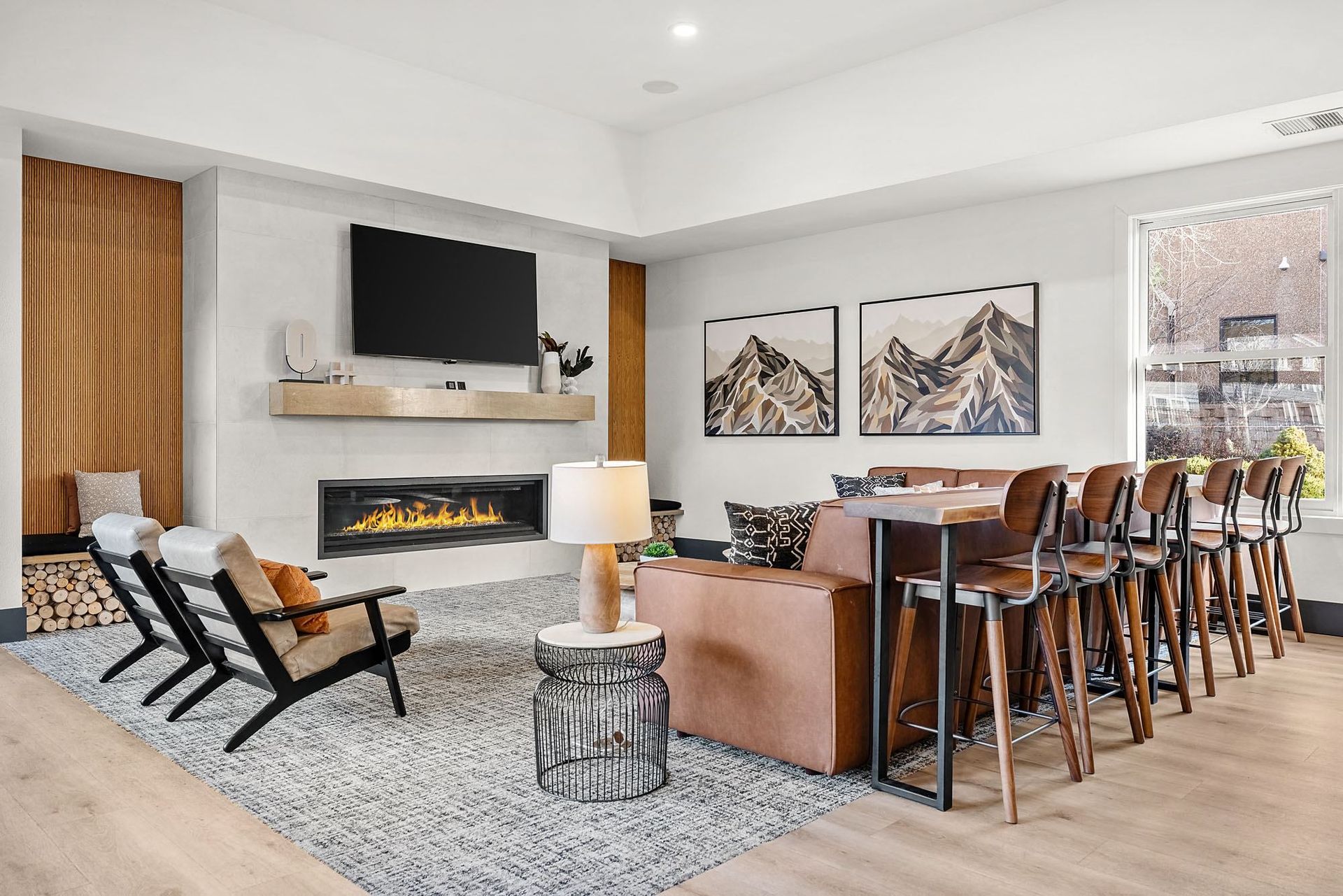 Modern apartment living room with a fireplace, wall-mounted TV, and bar-height dining counter at Briargate on Main apartments in Parker, CO.