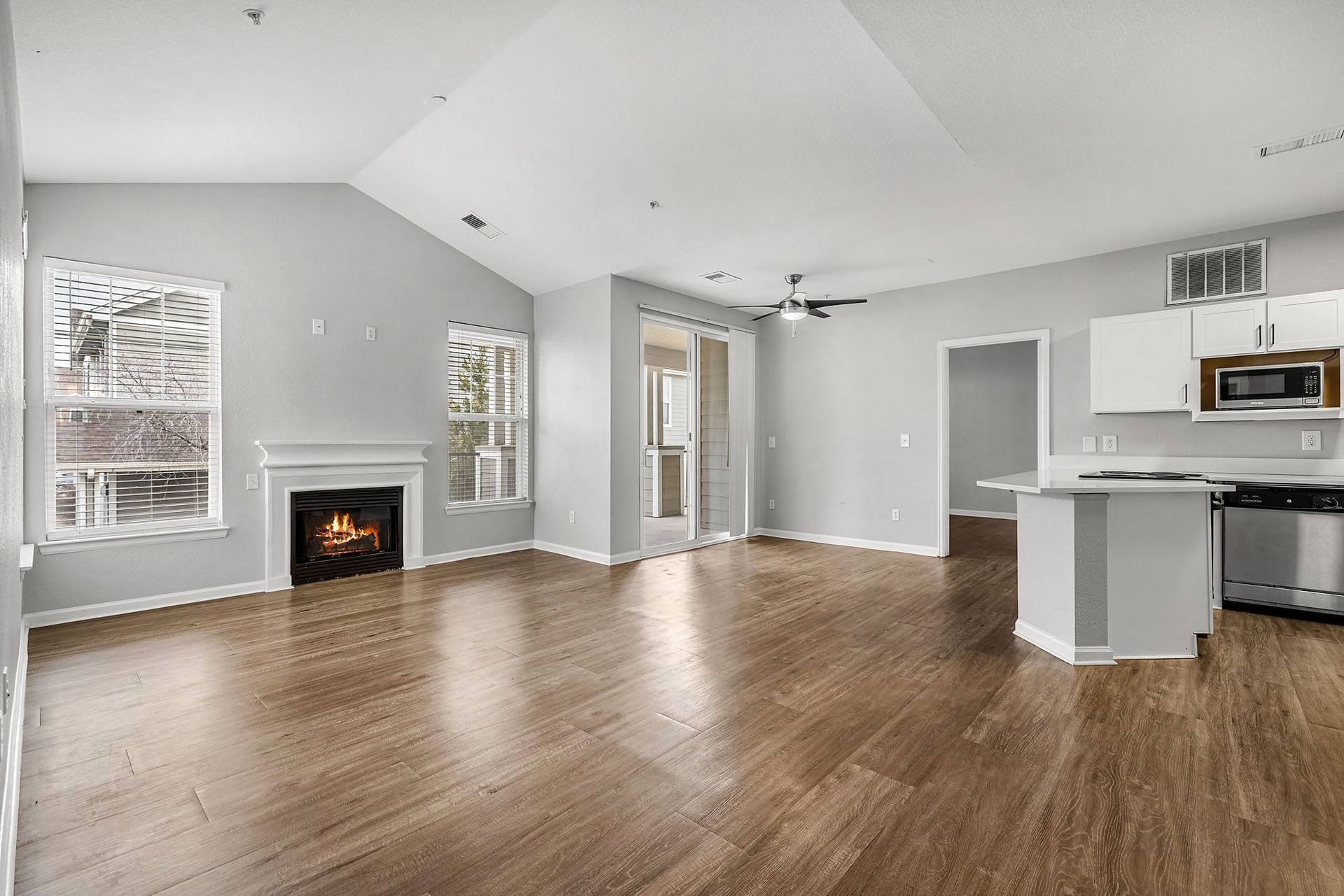 Living room with a gas fireplace, large windows, and an open kitchen in a modern apartment at Briargate on Main apartments in Parker, CO.