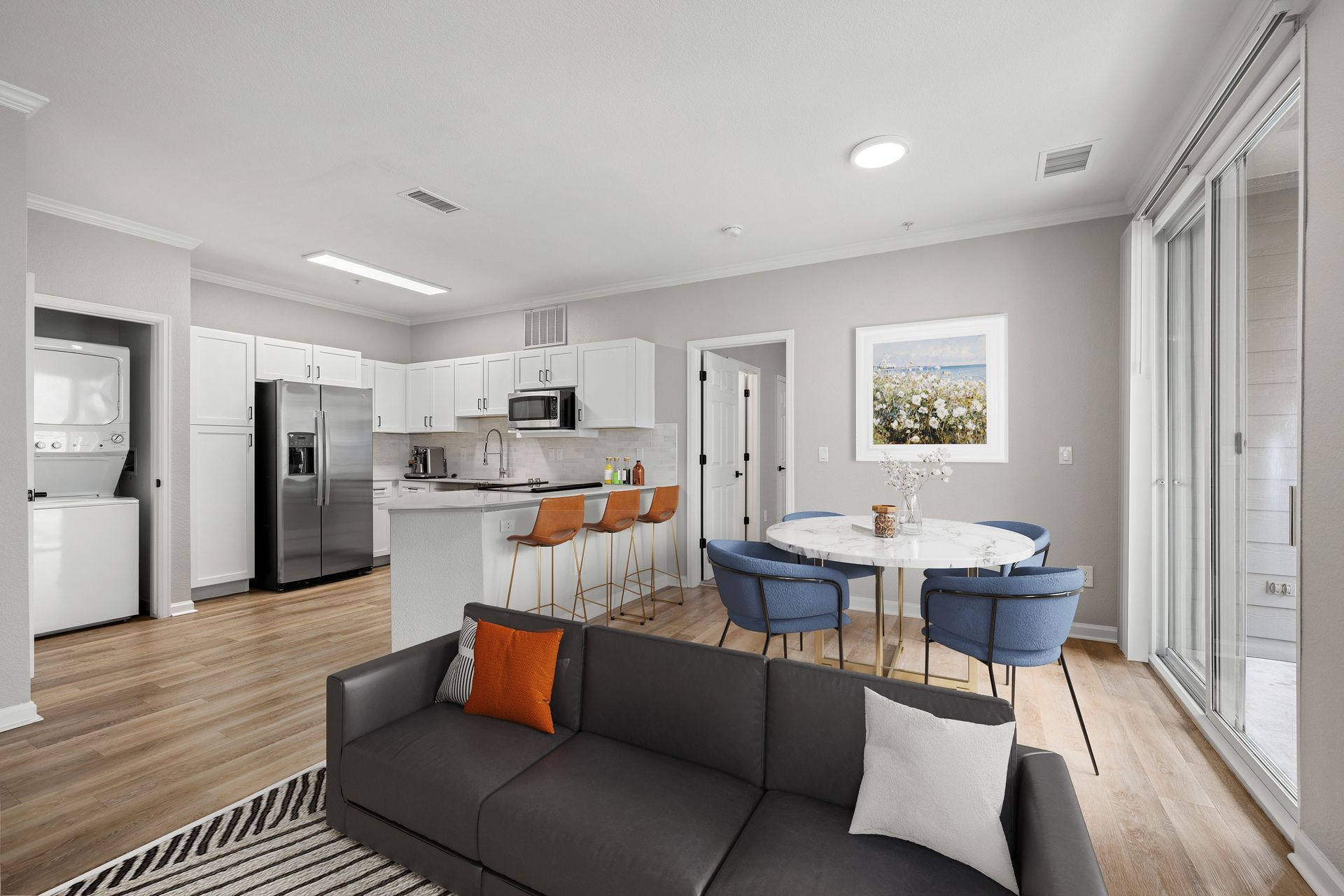 Open-concept living area with white cabinets, stainless appliances, an island, and a round dining table at Briargate on Main apartments in Parker, CO.
