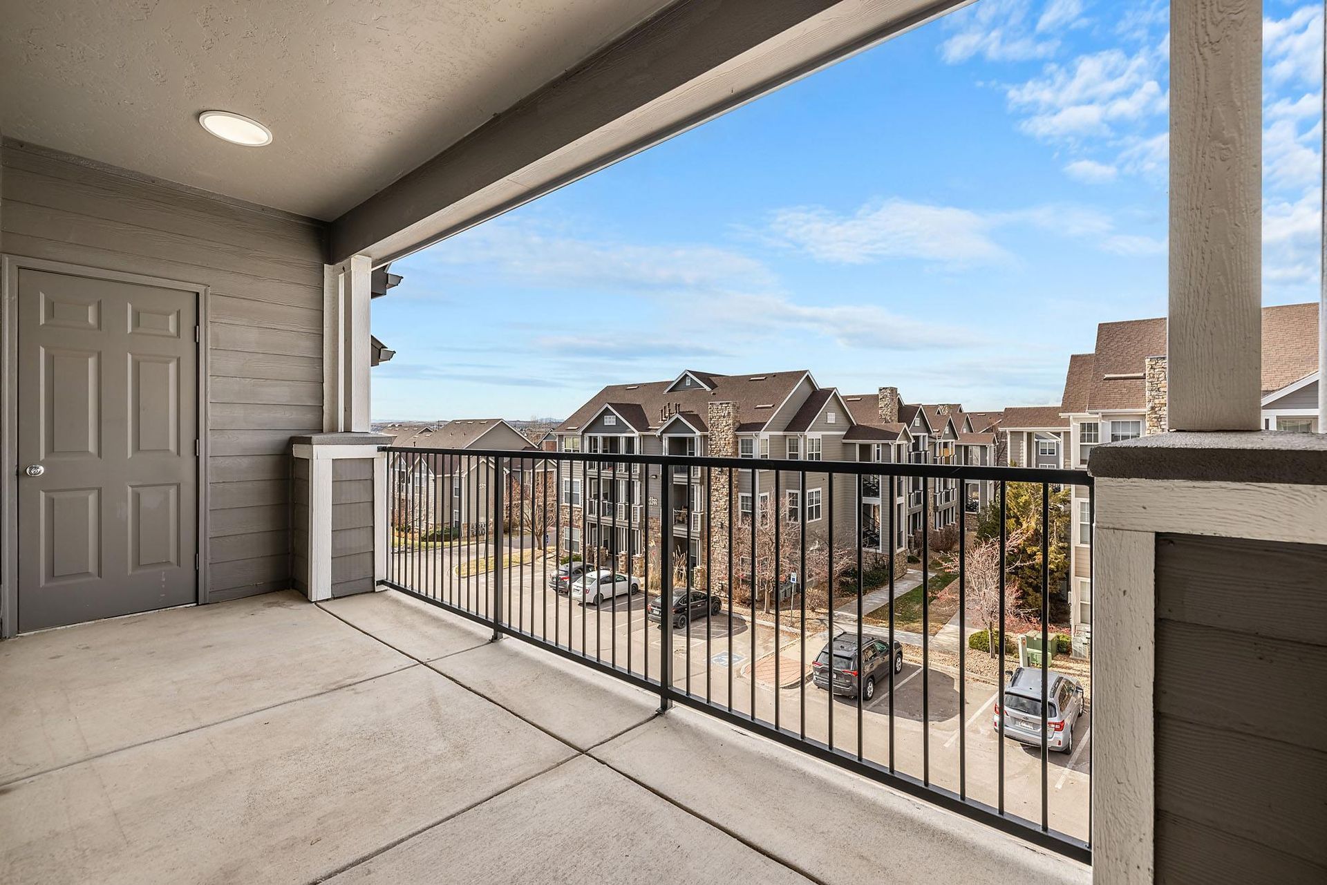Balcony view of a multi-building apartment complex with a parking lot below at Briargate on Main apartments in Parker, CO.