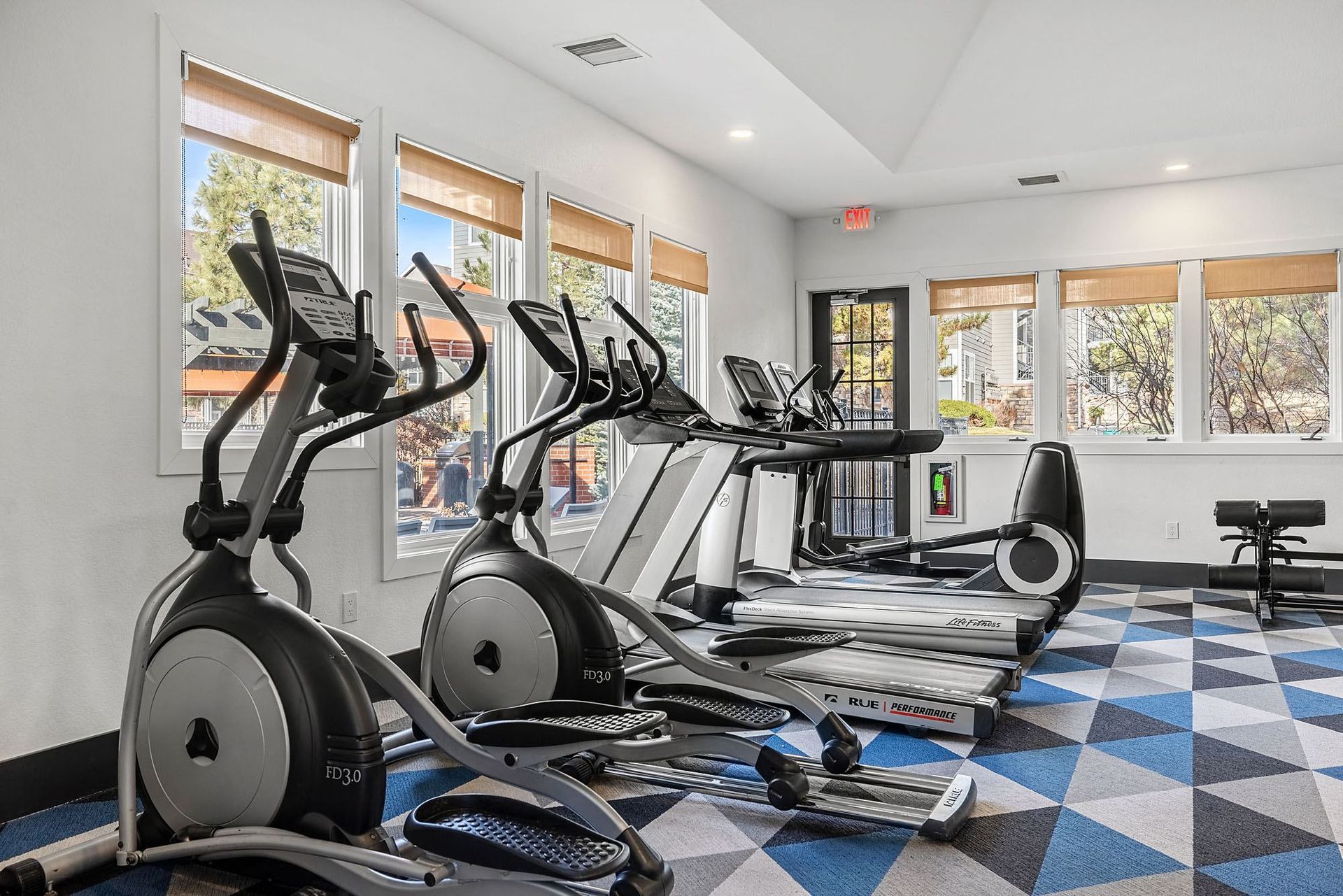 Fitness center with treadmills and elliptical machines by large windows at Briargate on Main apartments in Parker, CO.