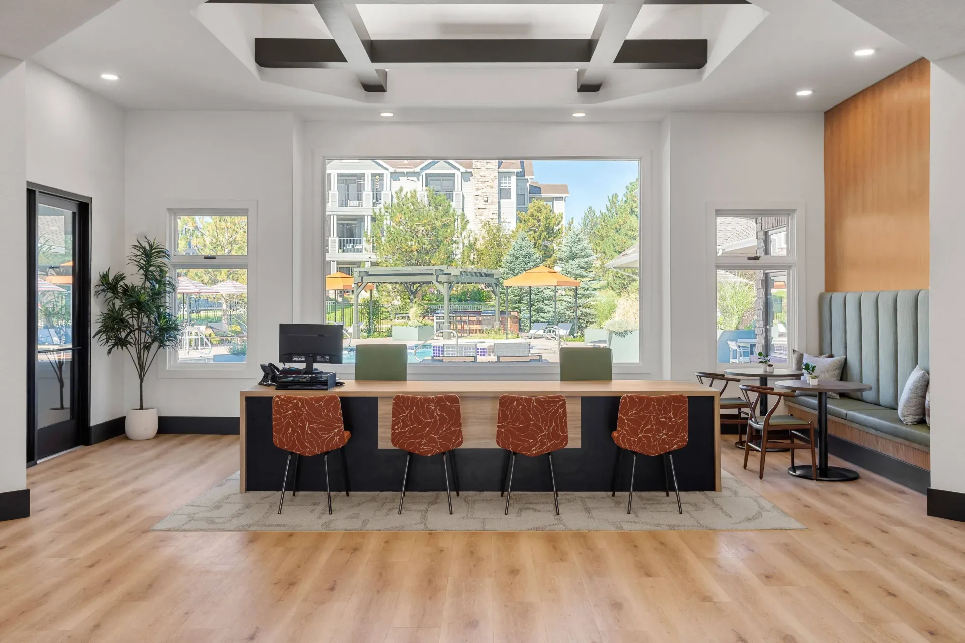 Modern leasing office reception with a large window view of the outdoor pool area at Briargate on Main apartments in Parker, CO.