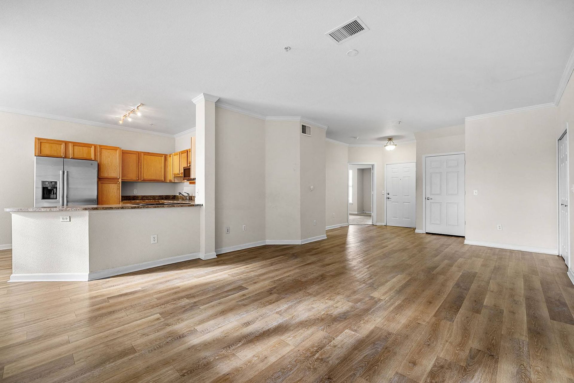 Open living area with kitchen and breakfast bar in an empty apartment at Briargate on Main apartments in Parker, CO.