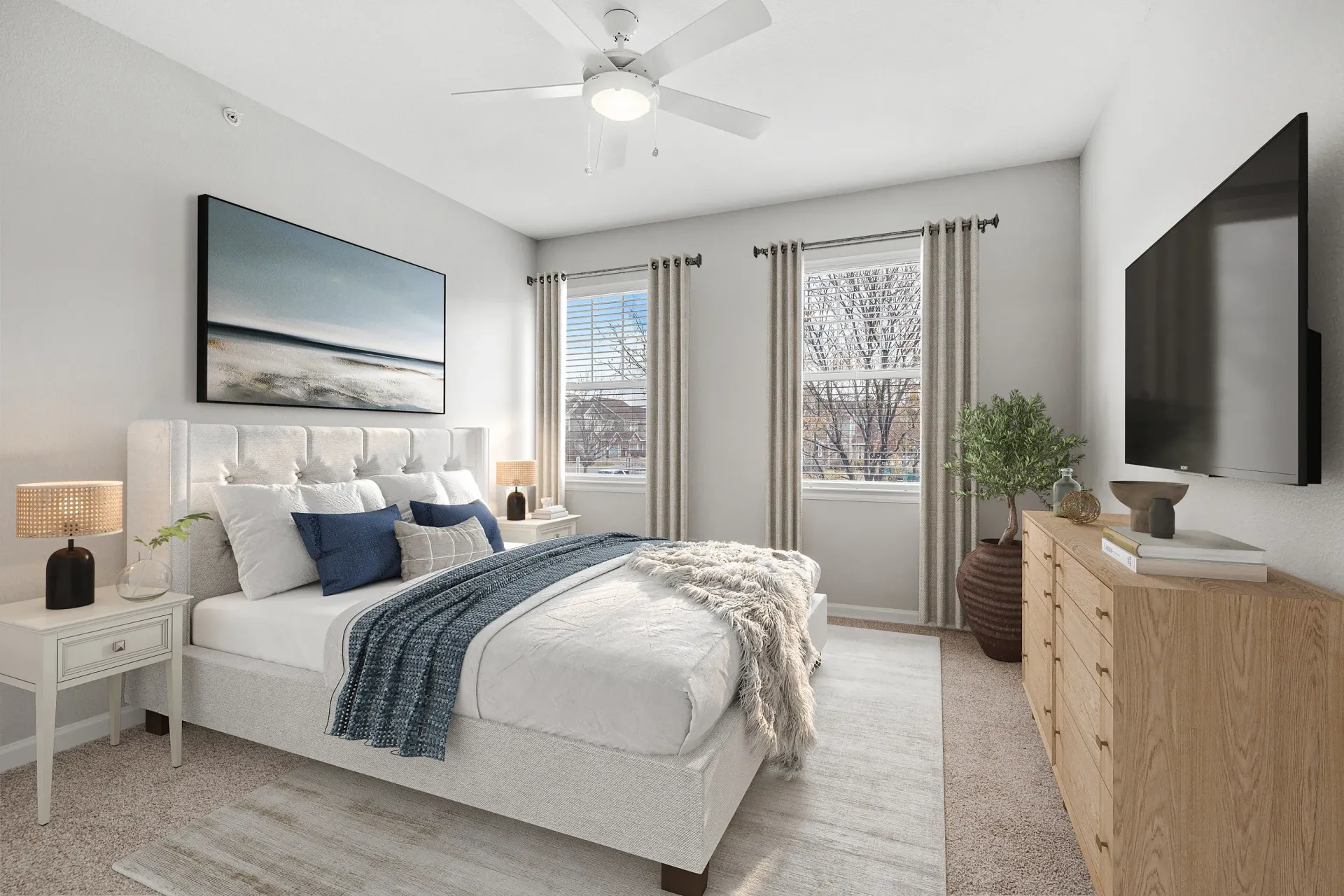 Bedroom in an apartment with a tufted headboard, two nightstands, a dresser, and a large window at Briargate on Main apartments in Parker, CO.