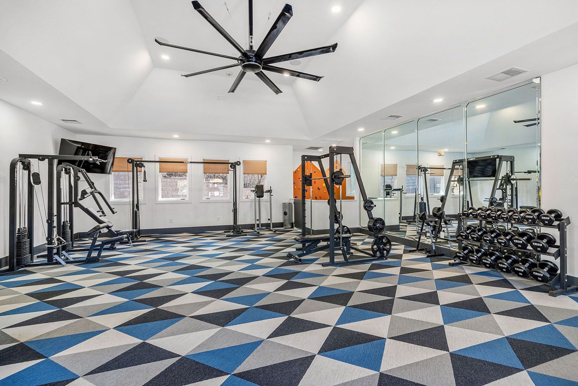 Bright apartment community gym with weight machines, free weights, and a mirrored wall at Briargate on Main apartments in Parker, CO.