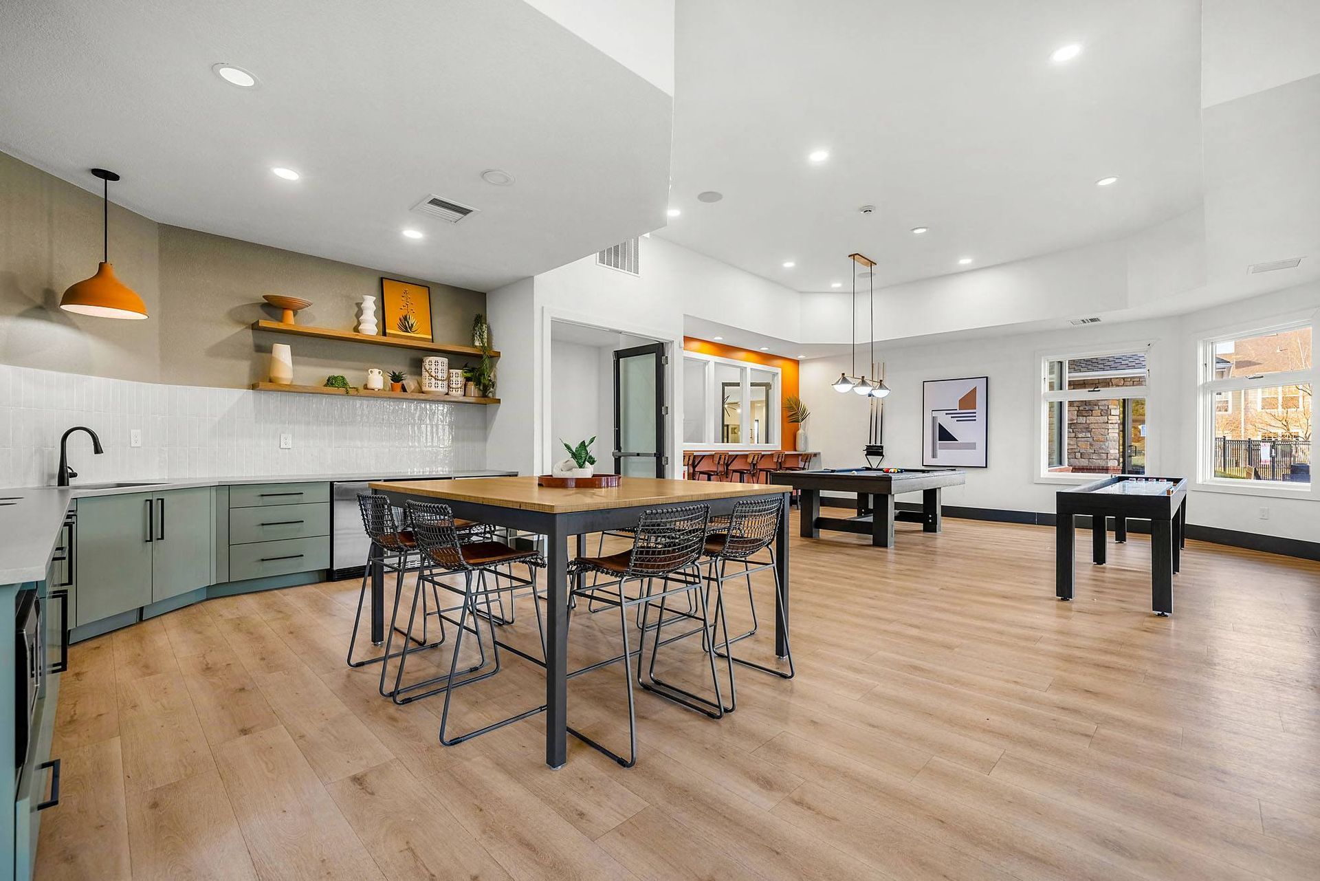 Bright community lounge with a kitchen island, seating, and a pool table area at Briargate on Main apartments in Parker, CO.