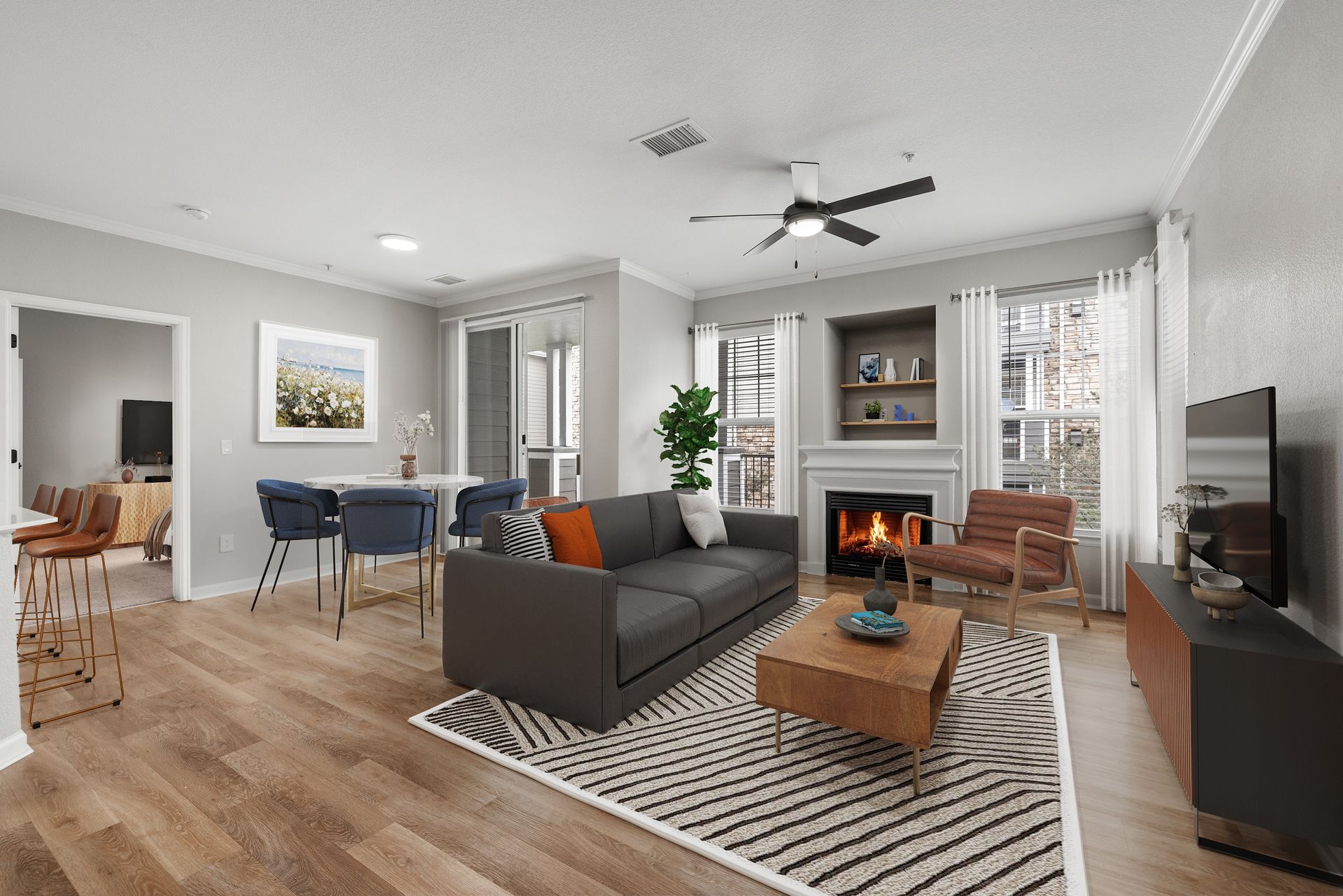 Bright living room in a modern apartment with a grey color palette, sofa, fireplace, and dining area at Briargate on Main apartments in Parker, CO.