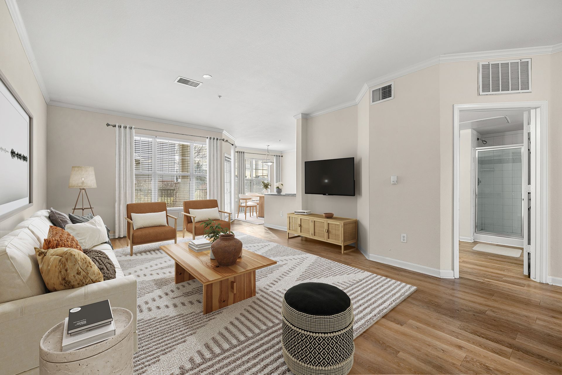Living room of an apartment with a sofa, two chairs, coffee table, rug, and wall-mounted TV at Briargate on Main apartments in Parker, CO.