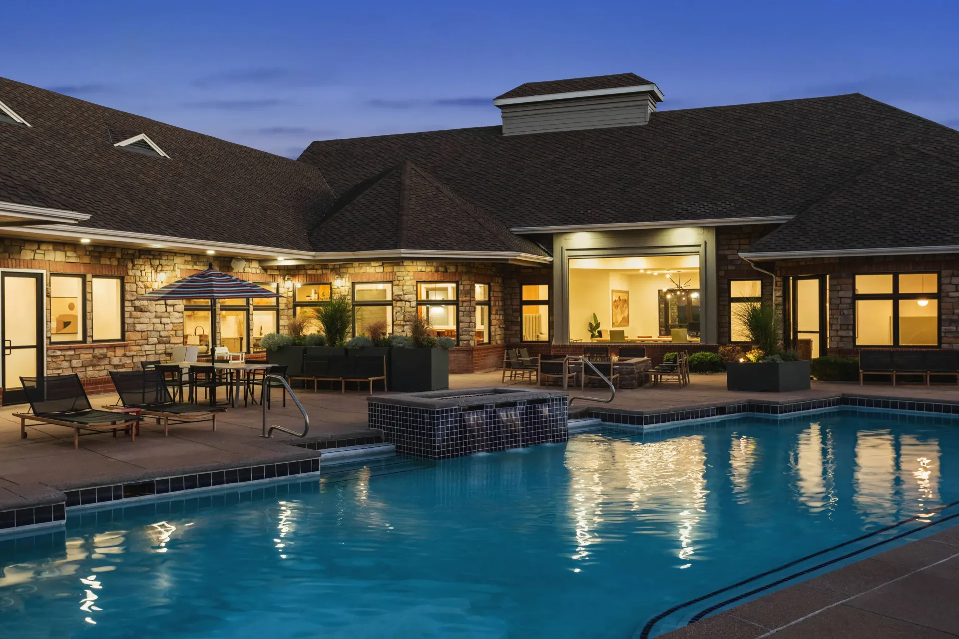 Outdoor pool area at an apartment community with lounge chairs and umbrellas at Briargate on Main apartments in Parker, CO.