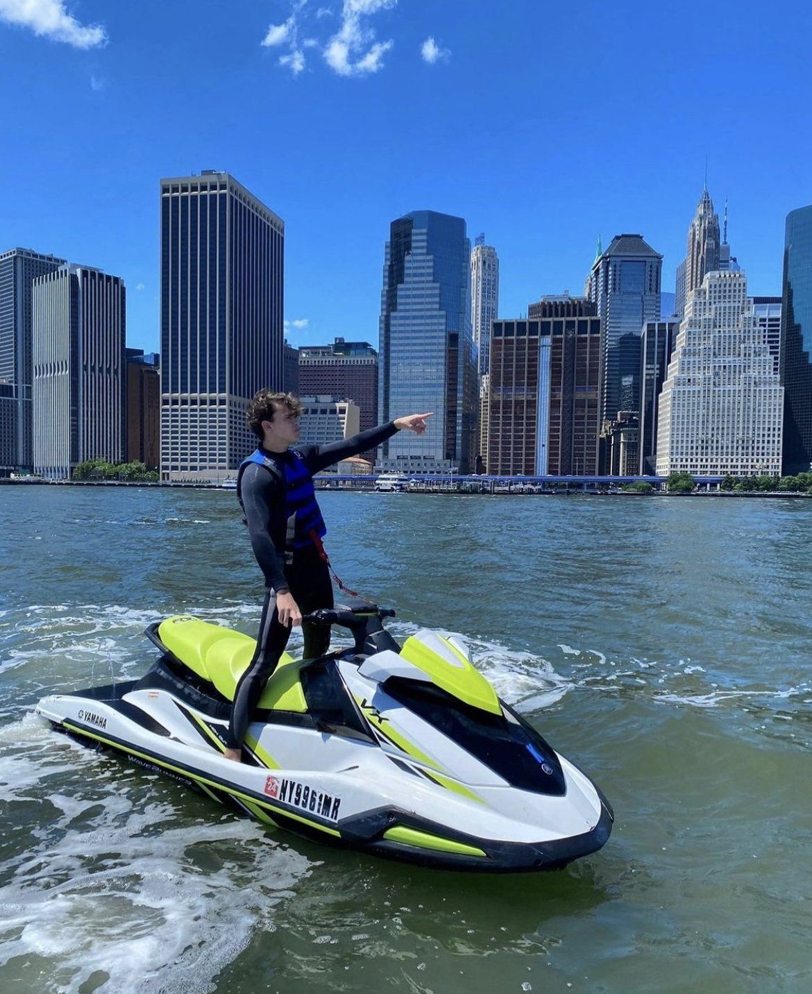 man standing on yellow jet ski and pointing