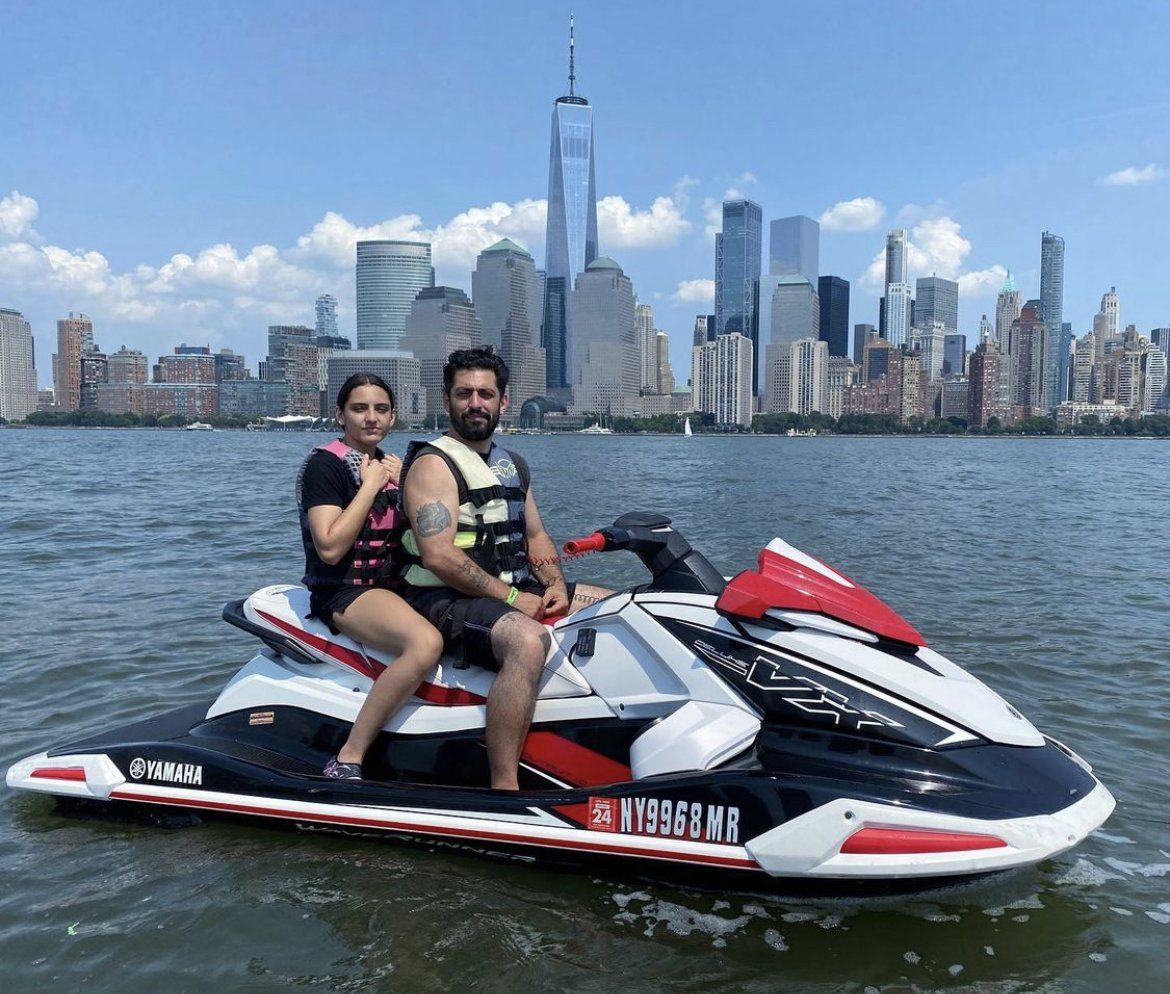 couple sitting on red and white jet ski