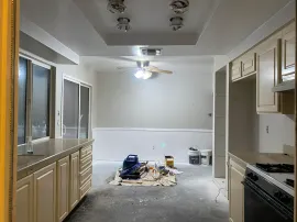 Renovated kitchen with light cabinets, white walls, and construction debris on the floor