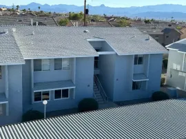 Apartment buildings with gray roofs and balconies, viewed from above with mountains in the distance