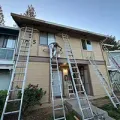 Two-story apartment exterior with five ladders leaning against the building during maintenance