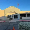 The Coronado Apartments entrance with a U.S. flag, orange cones, and a hedge in front.