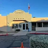 The Coronado Apartments entrance with a U.S. flag, orange cones, and a hedge in front.
