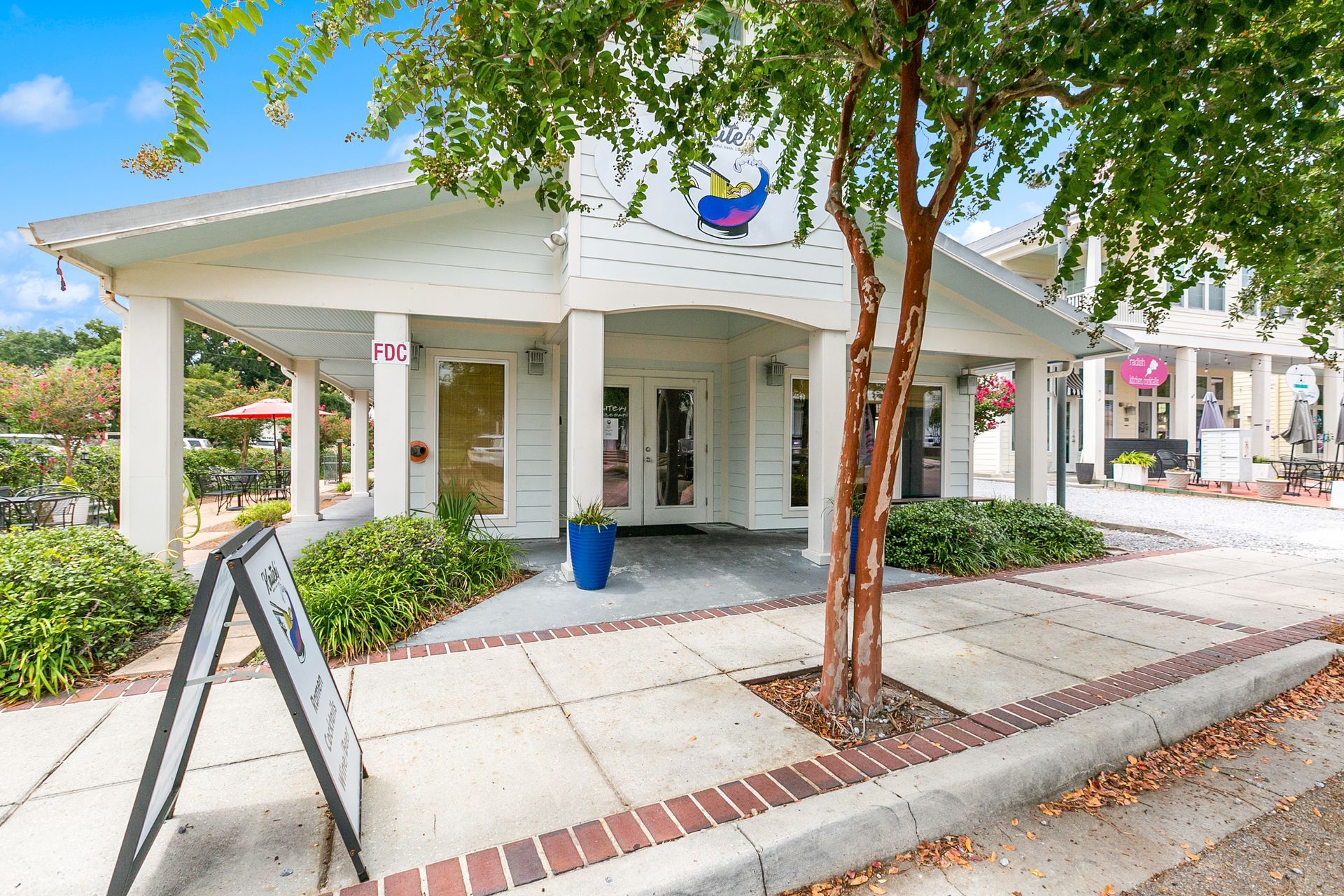 A white building with a sign on the sidewalk in front of it.