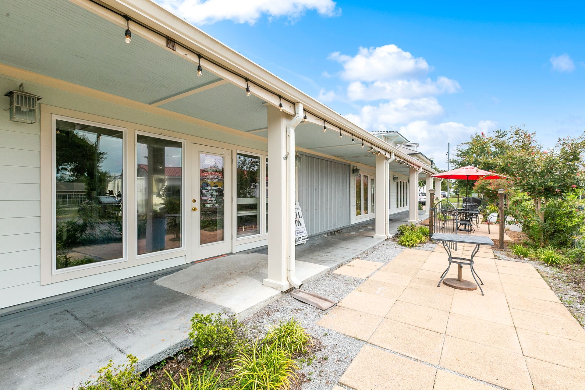 A white house with a patio and umbrella in front of it.