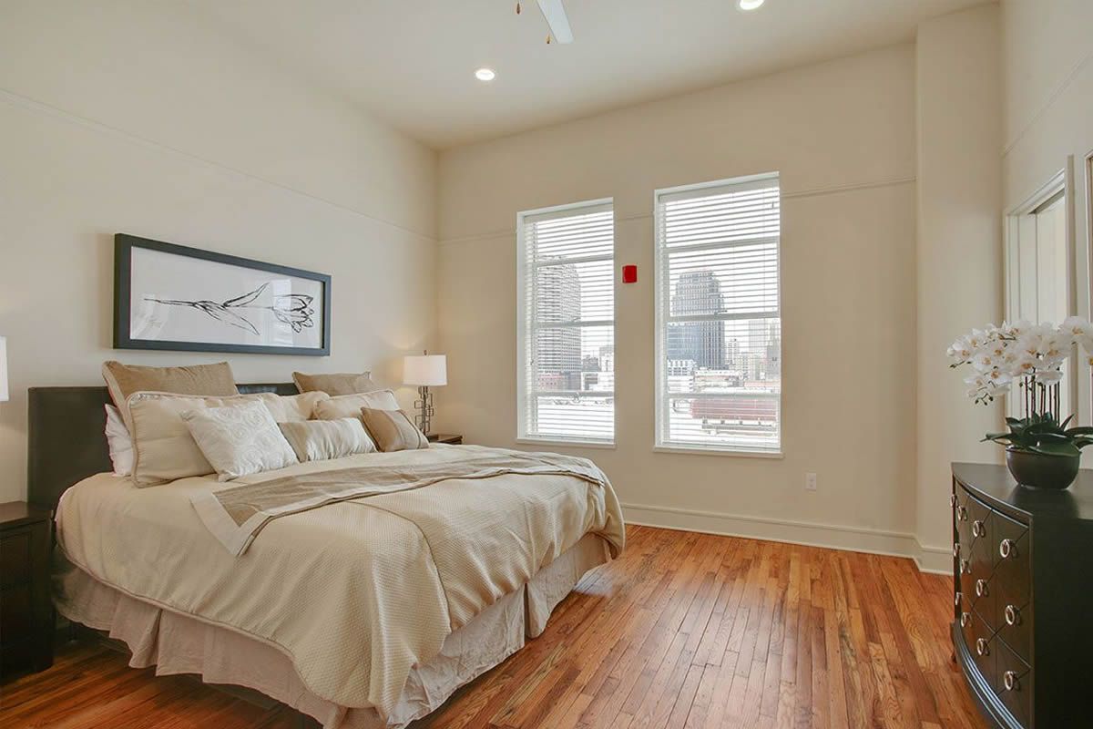 A bedroom with a bed , dresser , and two windows.