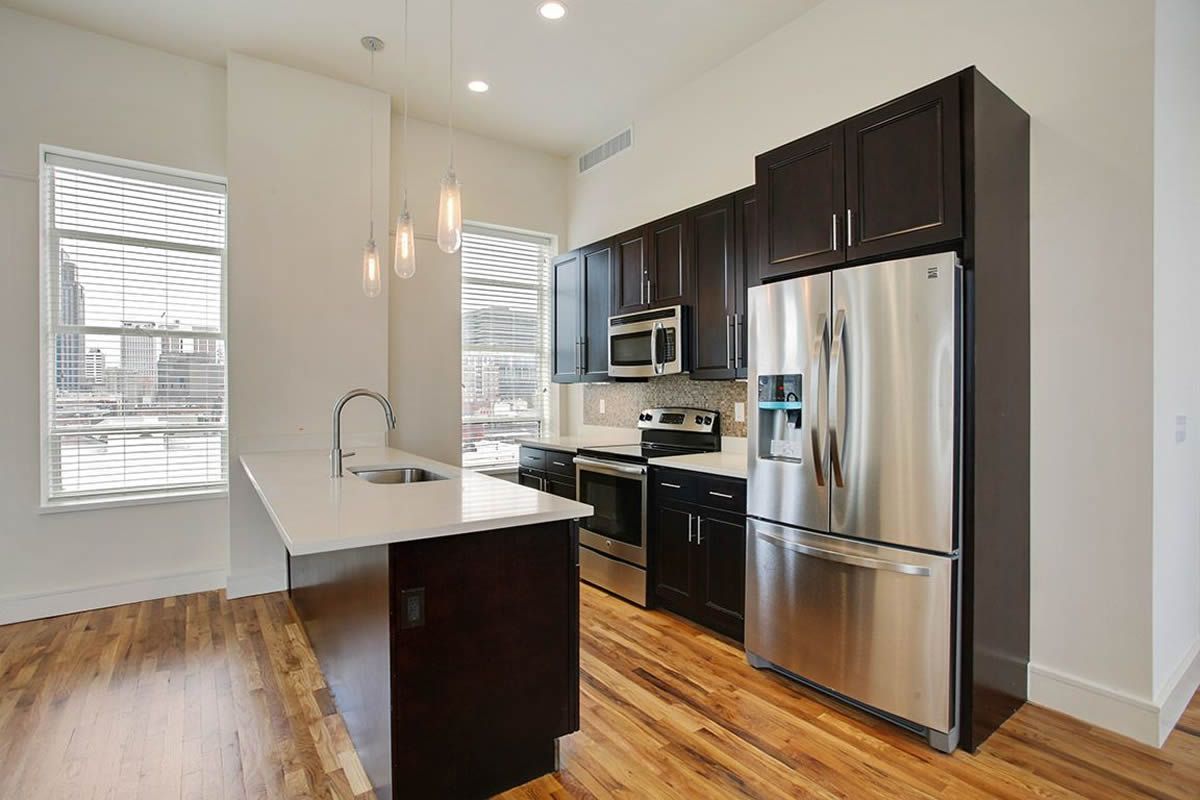 A kitchen with stainless steel appliances and wooden floors.