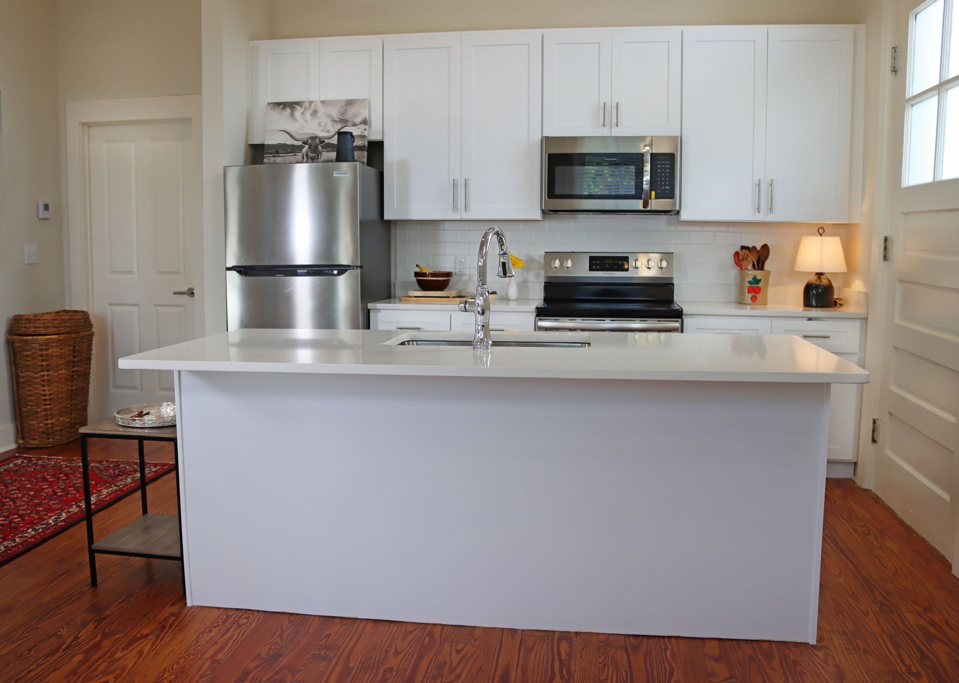 A kitchen with white cabinets , stainless steel appliances , and a large island.