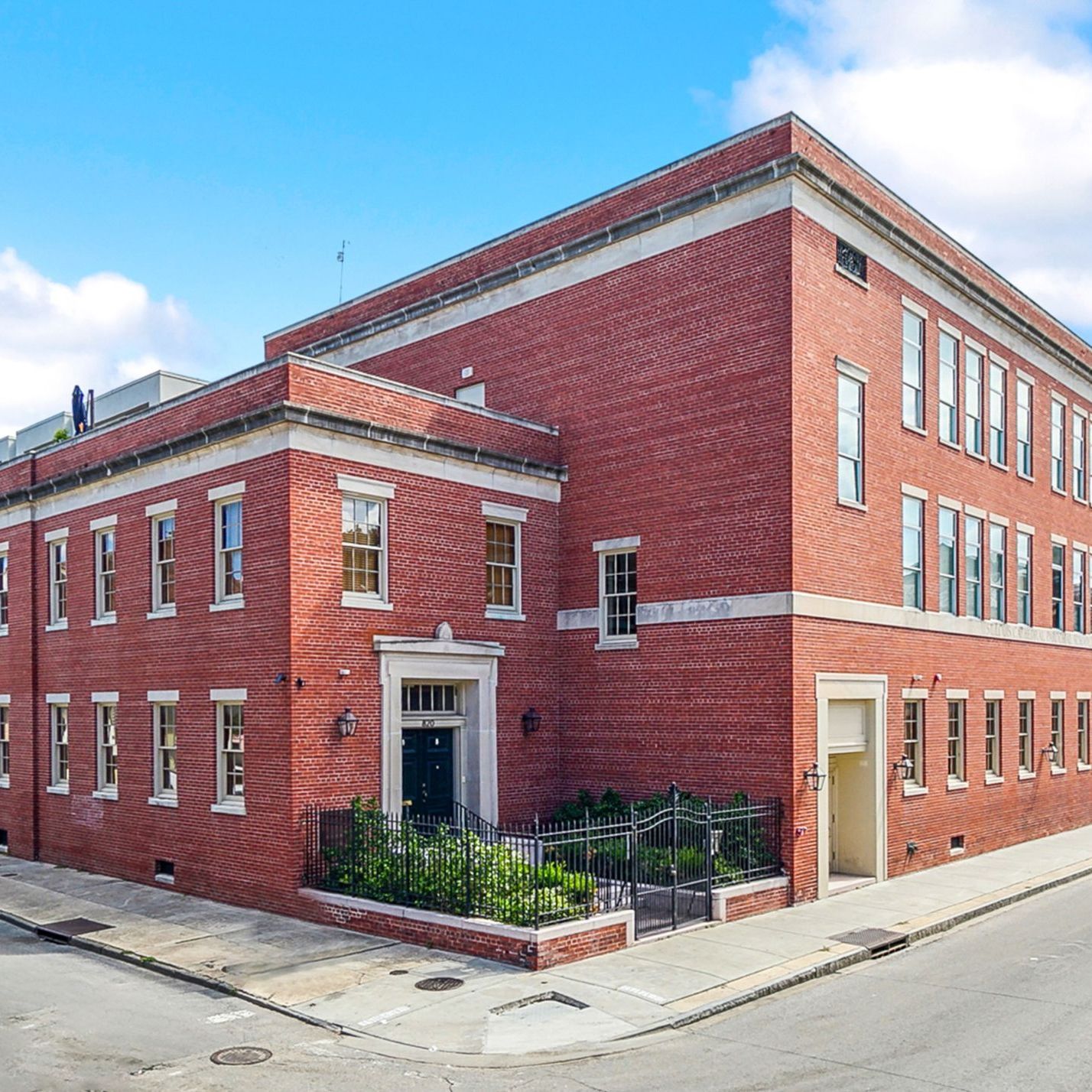 A large red brick building is on the corner of a street