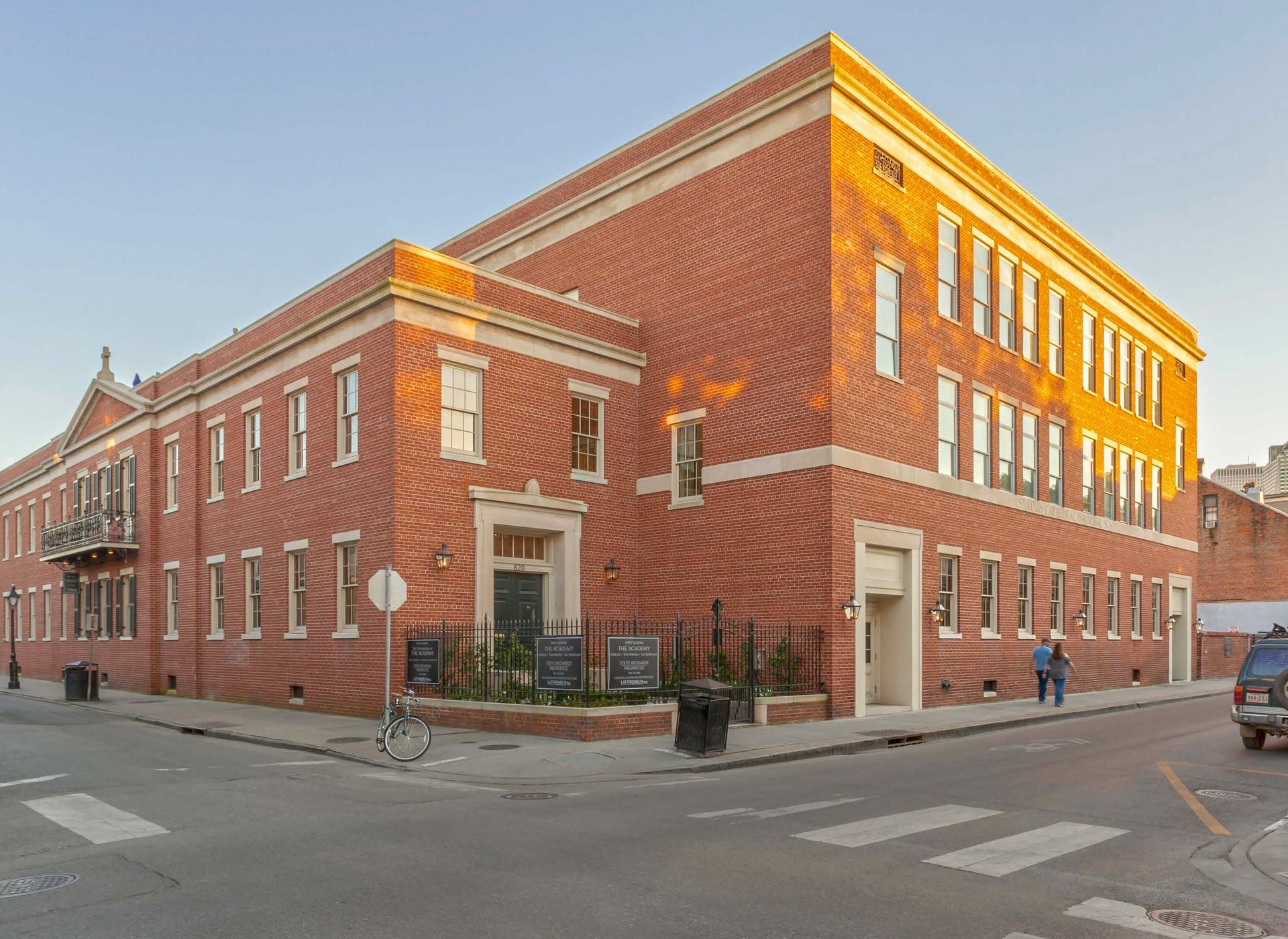 A large brick building is on the corner of a street.