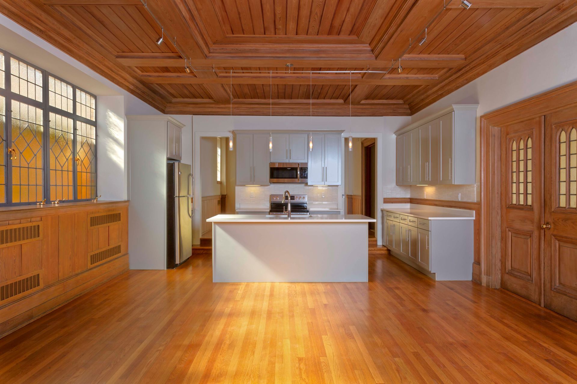 An empty kitchen with hardwood floors and a wooden ceiling