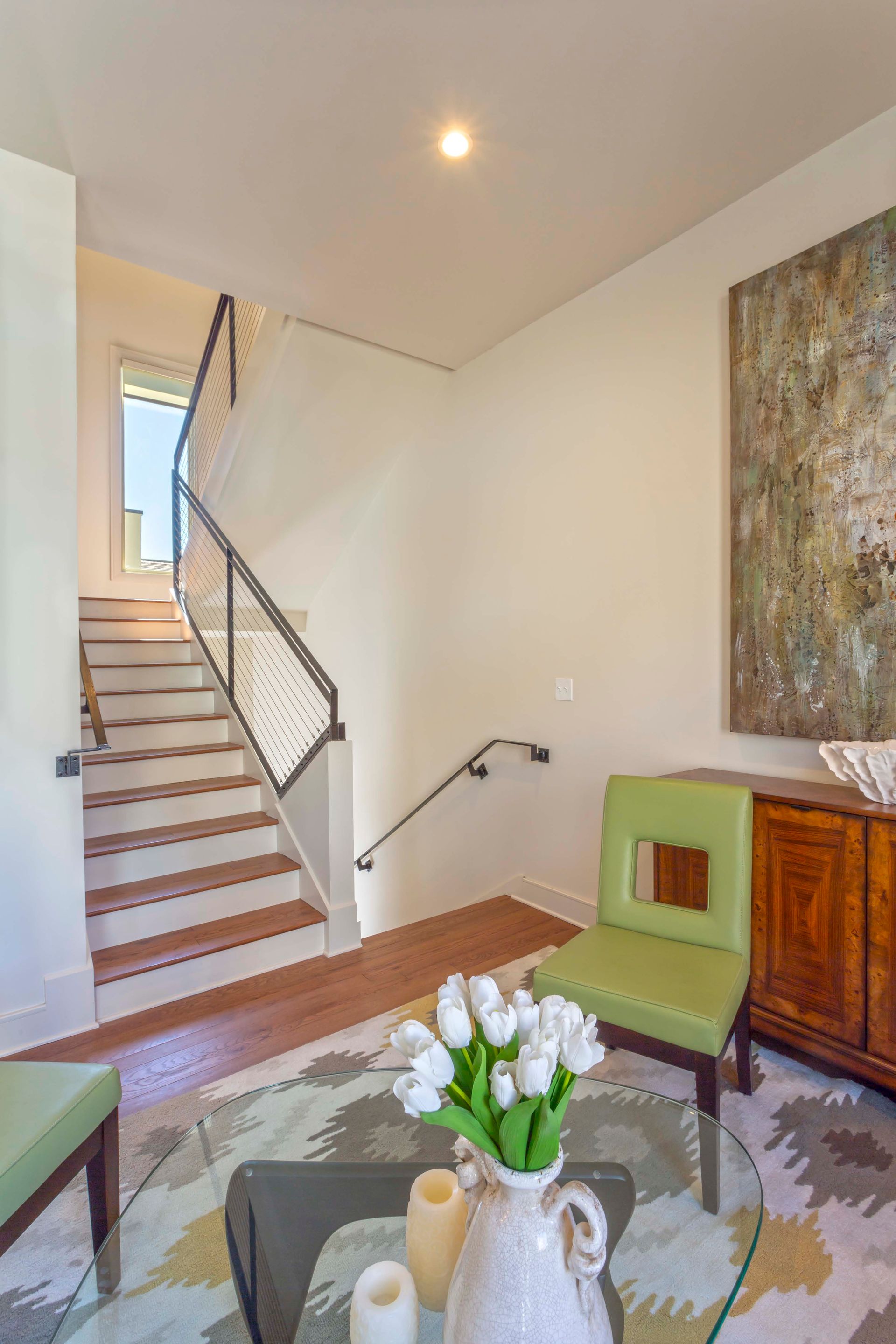 A living room with stairs and a vase of flowers on a table.
