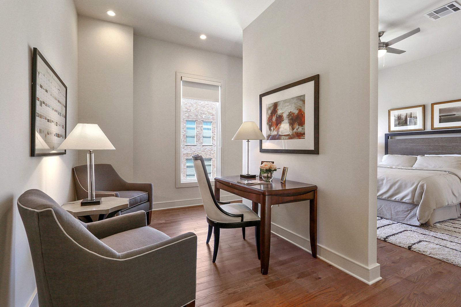 A living room with a desk , chairs , lamps and a bed.
