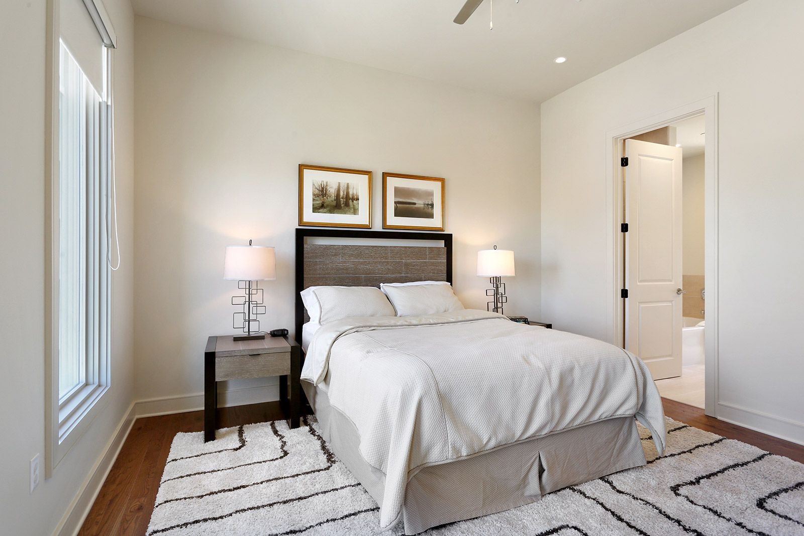 A bedroom with a bed , nightstand , lamps and a rug.