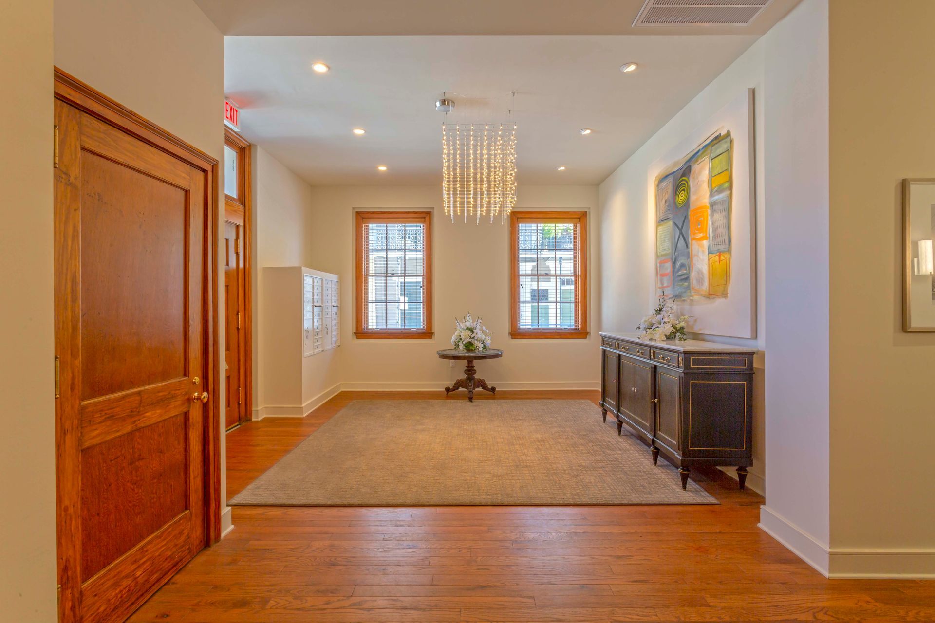 A large room with hardwood floors , a table and a chandelier.