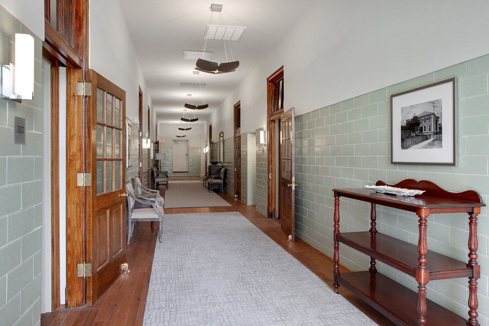 A long hallway with a wooden table and a picture on the wall.