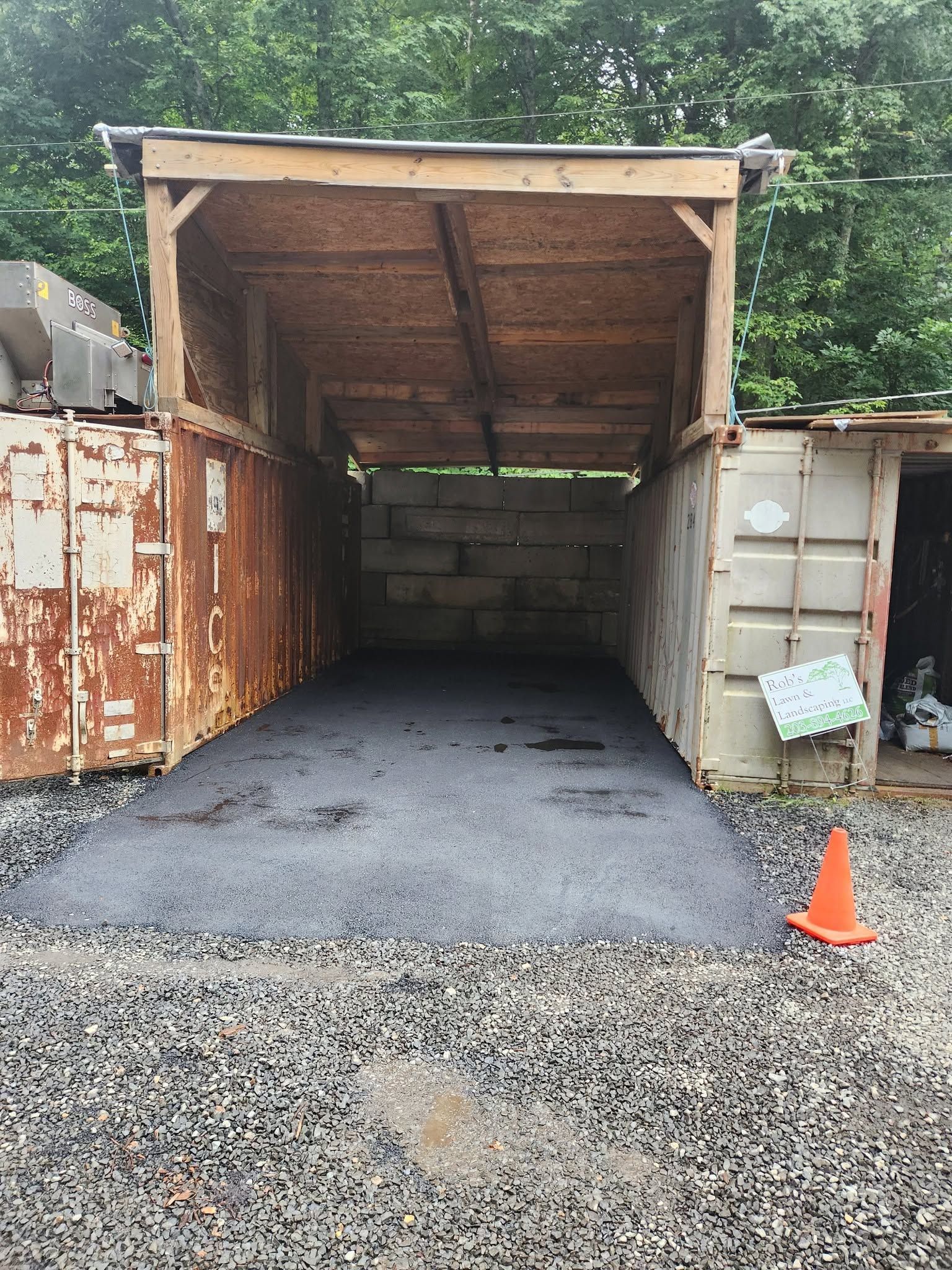 Open shipping container with gravel floor and an orange cone at the entrance