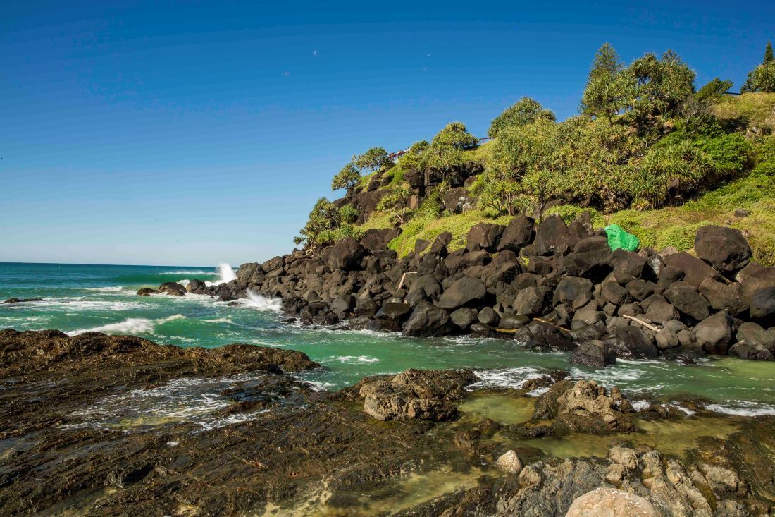 A Tent is Sitting on a Rocky Cliff Overlooking the Ocean — Top Shelf Glass Pool Fencing & Balustrading in Tweed Heads, QLD